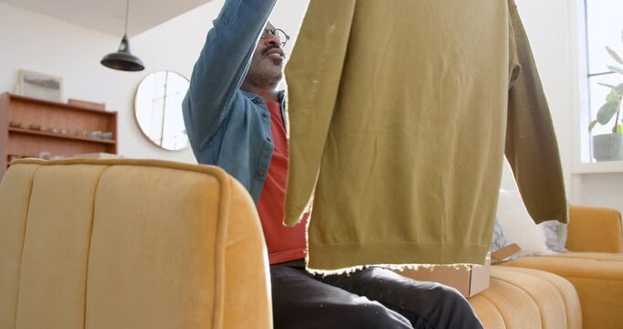 Man Opening Parcel with Clothing Bought Online at Home
