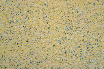 bright yellow exposed aggregate surface texture with speckled dark blue and green pebbles, detailed uniform construction background, concept of building material, architecture, modern flooring