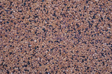 dark brown exposed aggregate surface texture with scattered black and tan pebbles, detailed uniform construction background, concept of building material, architecture, pathway design