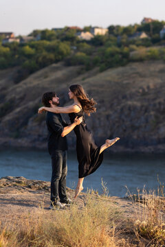 Man lifting woman in a romantic moment on a cliff by the river