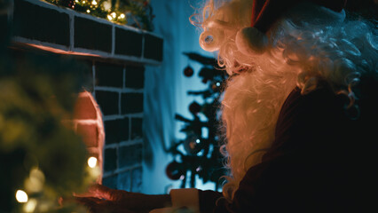 Sad and Cold Santa Claus Warms Himself by the Fireplace