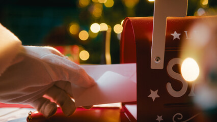 Santa Claus's Hand With Glove Opens Mailbox To Read Christmas Wishes