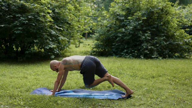 Man performing smooth mobility and roll transitions barefoot outdoors