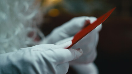 Santa Claus Reads Children's Wish Letters in His Hands