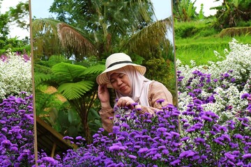 A calm moment of a woman touching purple blossoms surrounded by lush greenery and natural light.