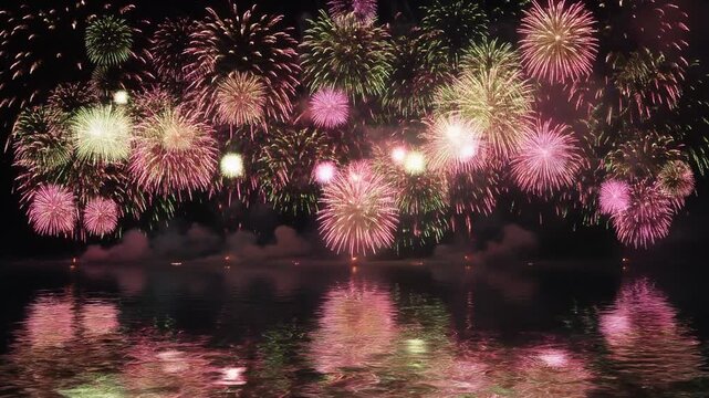 Fireworks exploding above calm water with shimmering reflections. Smooth motion and a large lower-third copyspace for titles or greeting