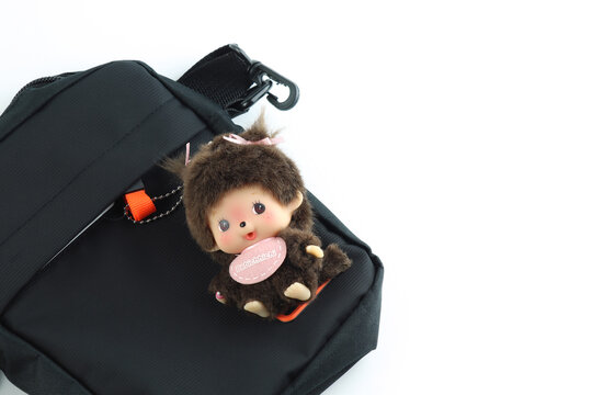 cute plush dolls key chain hang with black hand bag , Monchichi or Monchhichi , Japanese cute monkey fur doll display on white table white wall background in souvenir gifts tourists shop Japan dolls