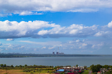 Power plant by lake under bright beautiful clouds