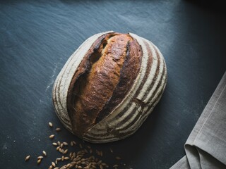 Sourdough bread loaf with a crispy crust and flour dusting on a dark background