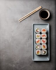 Sushi rolls served on a plate with chopsticks and soy sauce top down view