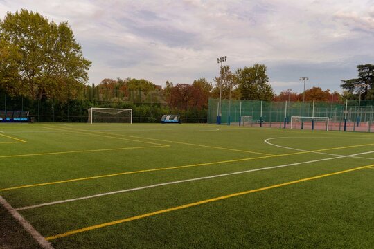 Empty soccer field with goalposts and surrounding sports facilities during cloudy afternoon