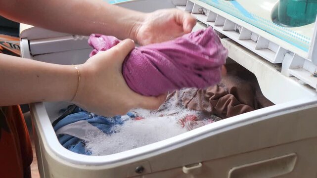 Closeup young asian woman housewife hand wring out and washing clothes by hand at home.