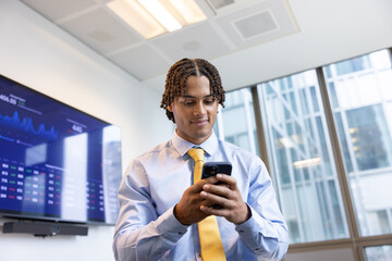 Businessman smiling while using smartphone in office setting