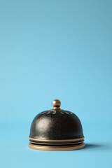 Antique black reception bell with golden accents isolated on a vibrant blue background