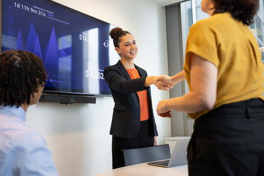 Young businesswoman in an office meeting the team with a handshake