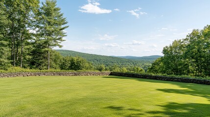 Expansive green lawn bordered by a stone wall leads to rolling hills and a bright blue sky