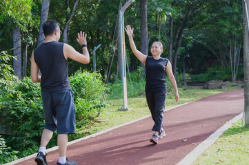 Active Asian Couple HighFiving During Outdoor Park Exercise