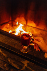 Close-up of a female hand with hot mulled wine. A woman in a sweater holds a delicious fragrant Christmas drink