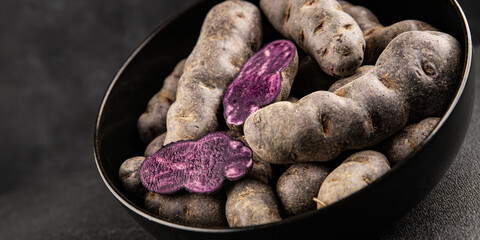 Purple potatoes raw fruit blue potatoe vegetable dish fresh gourmet food background on the table rustic food top view copy space keto and paleo diet vegan and vegetarian food
