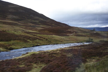 Scottish mountain loch in autumn surrounded by mountain peaks and rugged slopes, with water reflecting the dramatic highland landscape in Scotland
