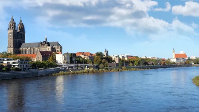 panorama of skyline oft he historical Magdeburg skyline, Germany, Elbe River in foregrund of downtown district, time lapse with motion blur on a sunny day with blue sky