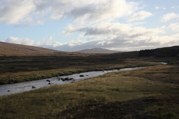 Scottish mountain loch in autumn surrounded by mountain peaks and rugged slopes, with water reflecting the dramatic highland landscape in Scotland