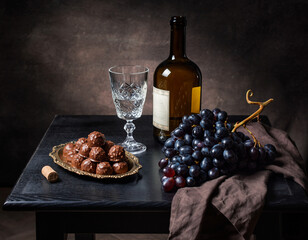 Luxury Still Life with Wine Bottle, Crystal Glass, Chocolate Truffles and Dark Grapes