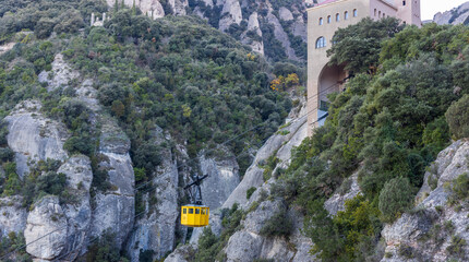 Yellow cable car is suspended above a rocky mountain