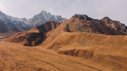 Vast Golden Mountain Landscape with Distant Snow-Capped Peaks