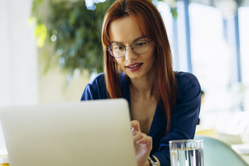 Young business woman sitting in a cafe and working on her laptop