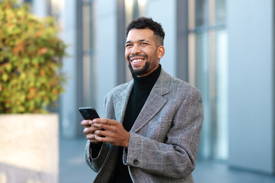 Smiling man in suit with smartphone on city street