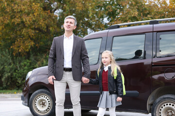 Father taking his daughter to school near car outdoors