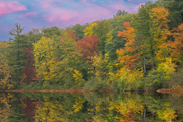 Fototapeta premium Autumn landscape at dawn of the shoreline of Long Lake with mirrored reflections in calm water, Yankee Springs State Park, Michigan, USA