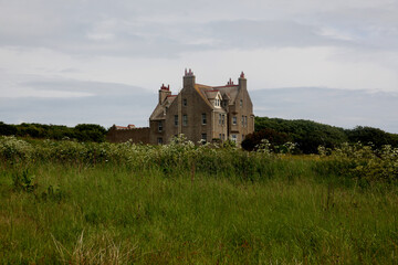 Abandoned ancient stone house in the wild Scottish Highlands, a remote ruined building surrounded by rugged moors, green fields, misty atmospheric landscape and dramatic overcast skies  rural Scotland © faestock