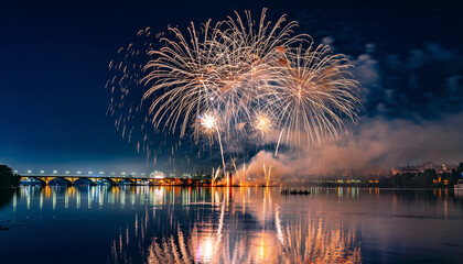 Fireworks explode over a city skyline reflected in water at night.