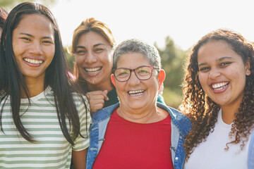 Multiracial women smiling on camera at city park - Multi generational group of people outdoor - Community, diversity and feminism concept