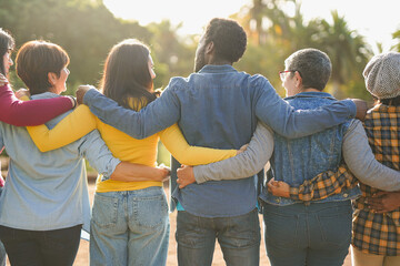 Group of multiracial people hugging each other at city park - Back view of multi generational community outdoor - Humanity, social inclusion and diversity concept