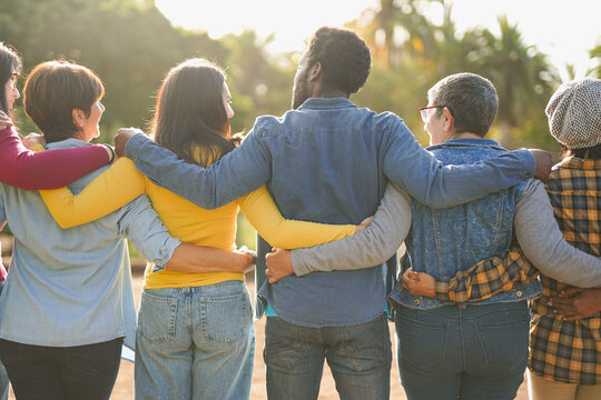 Group of multiracial people hugging each other at city park - Back view of multi generational community outdoor - Humanity, social inclusion and diversity concept