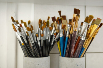 Collection of paintbrushes arranged in holders on a work surface in an artist studio