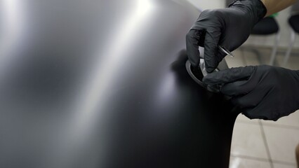 Worker hands wrapping car door handle with matte vinyl