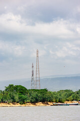 Nature and Industry: Tall Electric Transmission Towers Overlooking a Green Shoreline