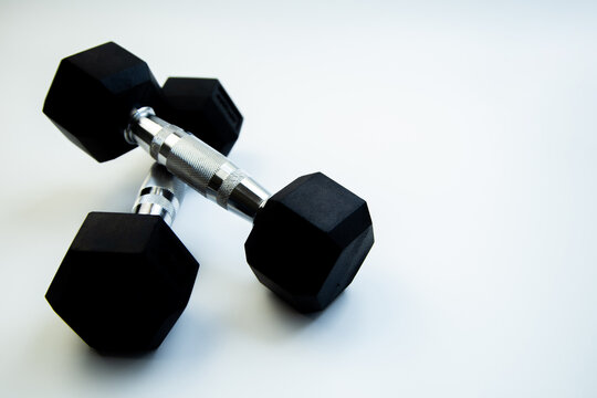 Hexagonal dumbbells with a sleek design are placed on a smooth white background, ideal for fitness enthusiasts and promoting strength training activities