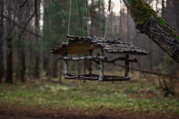 Handmade wooden birdhouse on a tree in the forest. Rustic made of natural wood and branches