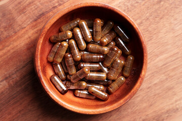 Supplement capsules with herbal extracts in a wooden container