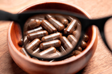 Brown pharmaceutical medicinal capsules focused through glasses.
