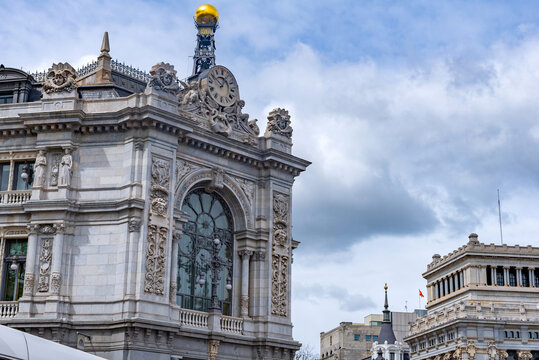 The grand stone facade of the Banco de Espa&ntilde;a in Madrid shows detailed carvings, tall arched windows, and a golden dome crowning a corner tower with refined detailing