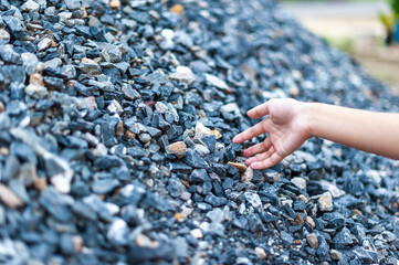 Hand reaching for stones outdoor construction site natural environment close-up texture exploration