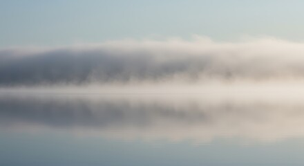 Horizontal layer of mist hovers just above the still surface of calm water