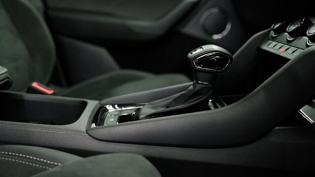 Modern car interior details featuring the dashboard, manual gear shift, and passenger seat with alcantara upholstery and white stitching