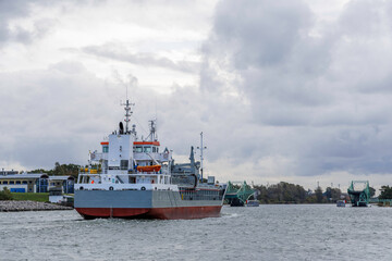Fototapeta premium Cargo Ship Maneuvering in Channel Near Twin Swing Bridges